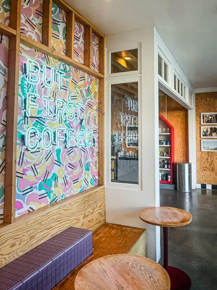 the inside of Alfred Coffee on Abbot Kinney, including the but first, coffee sign, a few tables and photographs on the wall.